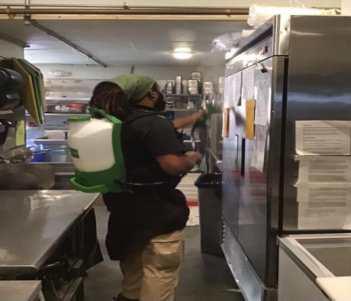 technician sanitizing commercial grade fridge