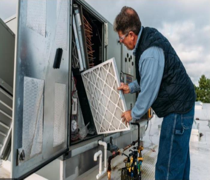 man replacing filter in commercial hvac system